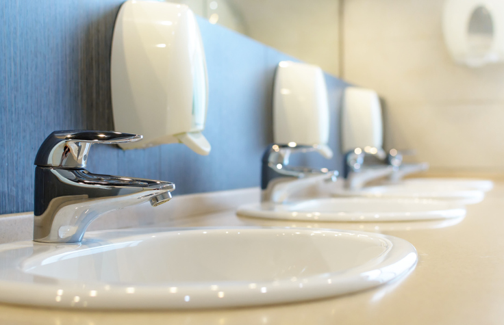 Silver faucet and white sink in a new public toilet room empty. Shallow DOF